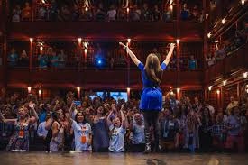 Photo: Woman with Raised Arms Standing in Front of a Crowd of People